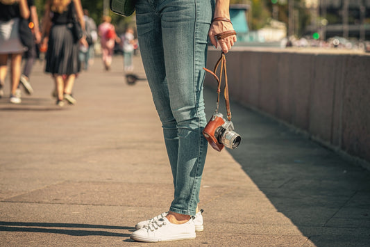a woman is holding a camera and walking down a sidewalk