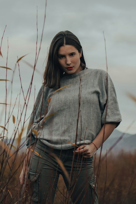 woman in gray knit shirt and brown plaid pants standing on grass field during daytime
