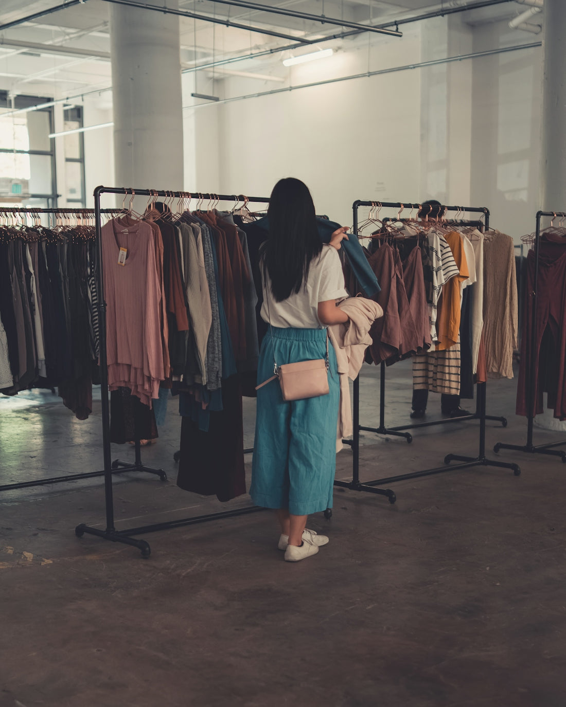 a woman standing in front of a rack of clothes