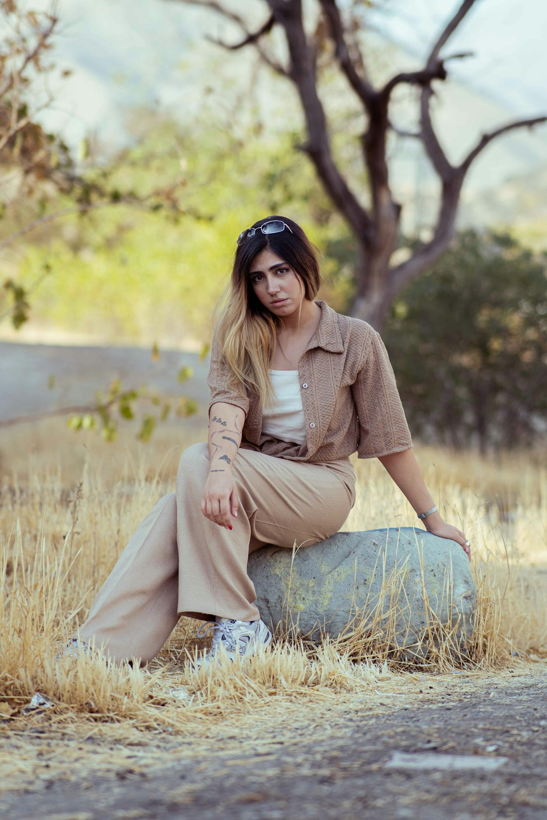 A young woman sits on a rock outdoors.