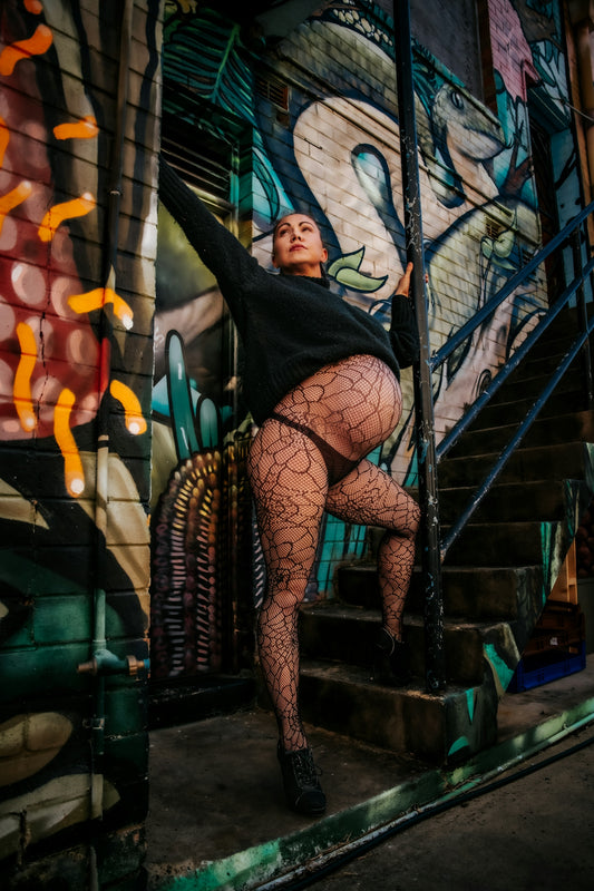 Pregnant woman posing against graffiti art