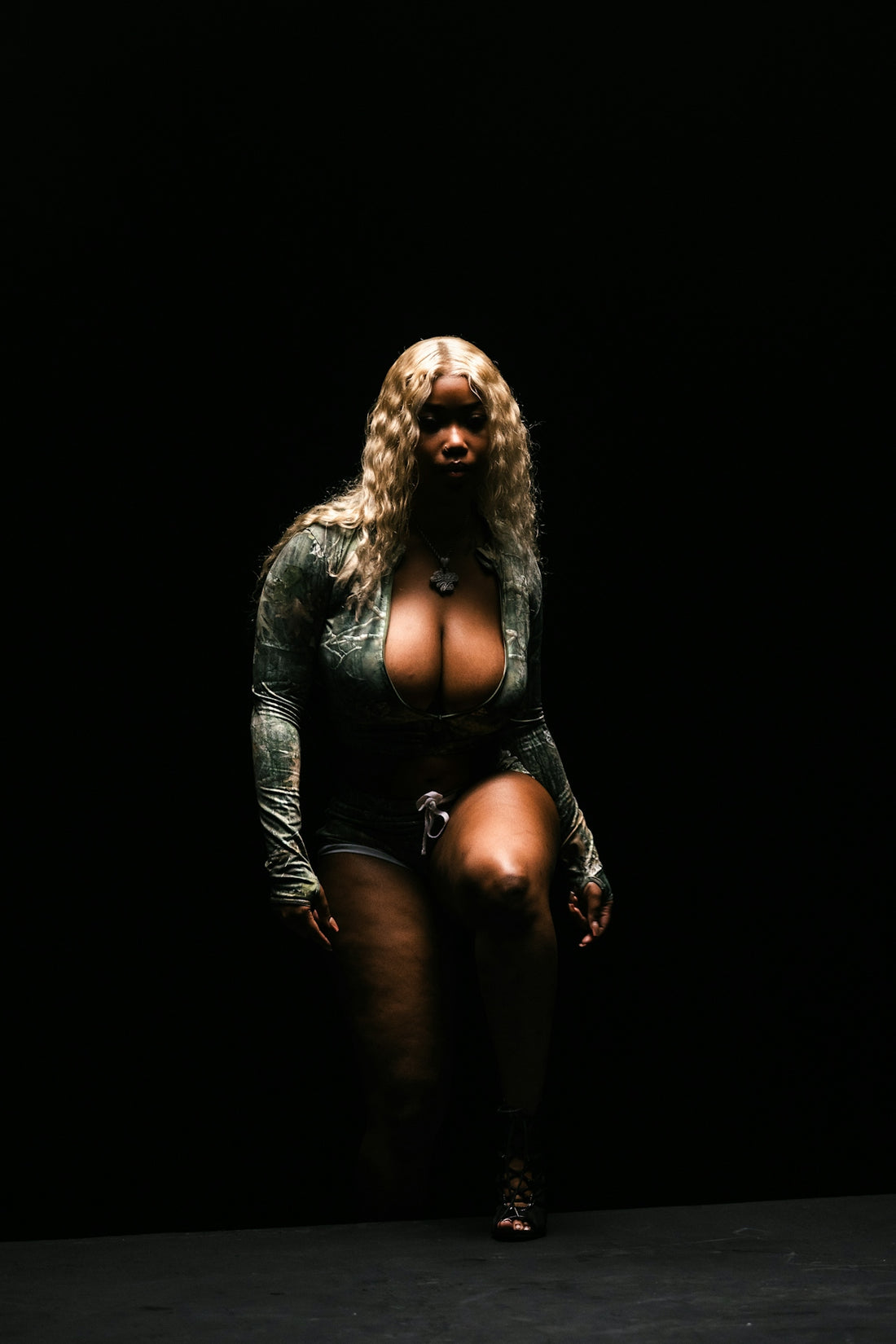 A woman with blonde hair poses in a dark room.