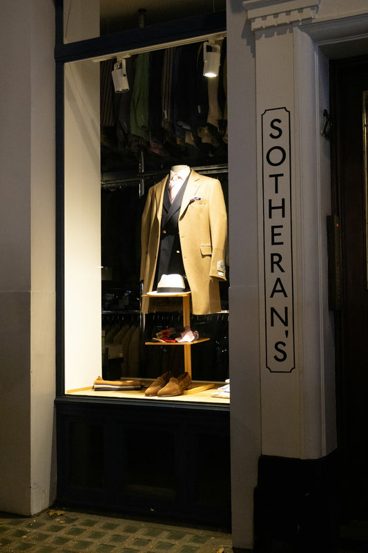 Mannequin in a tailored suit displayed in a shop window.