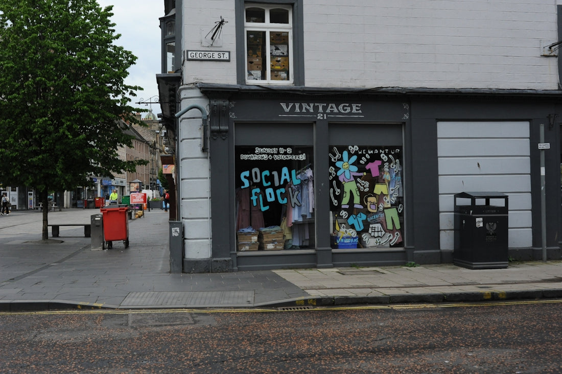 Vintage clothing store with colorful window display on city street.