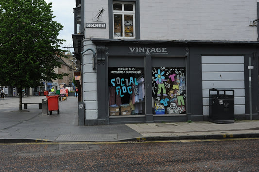 Vintage clothing store with colorful window display on city street.
