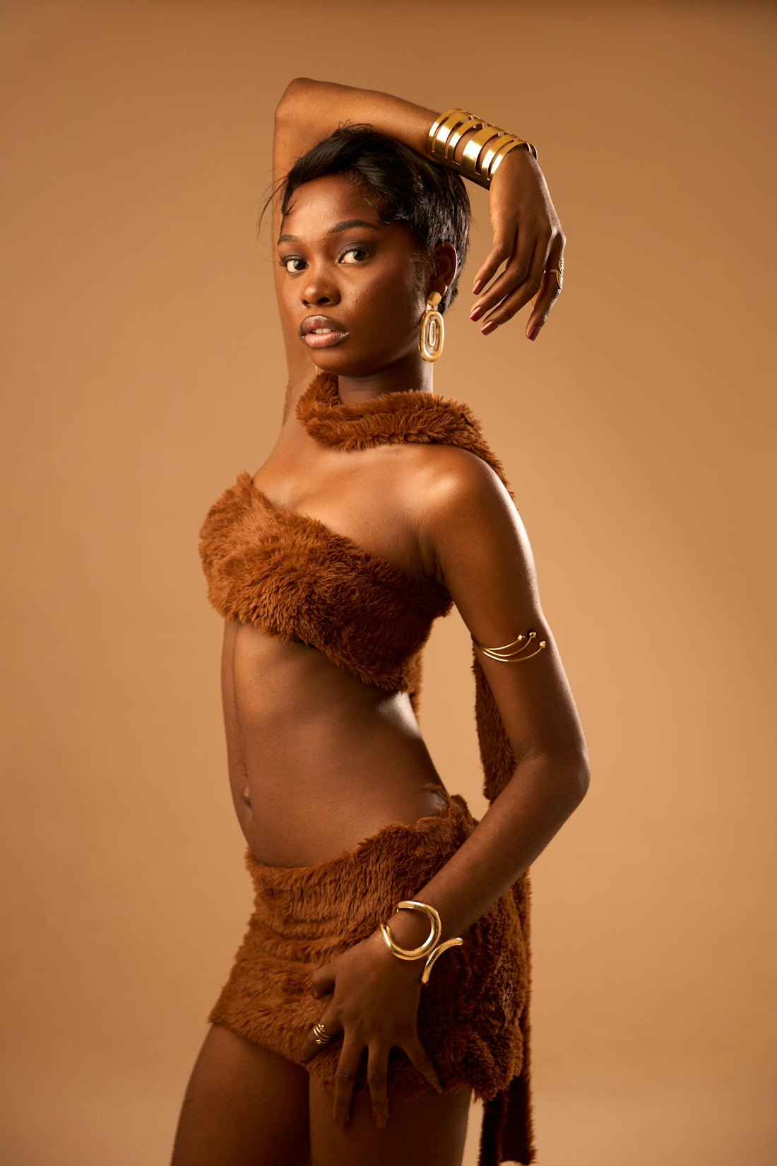 Beautiful woman in a brown furry outfit with gold jewelry.