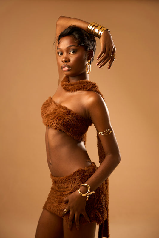 Beautiful woman in a brown furry outfit with gold jewelry.